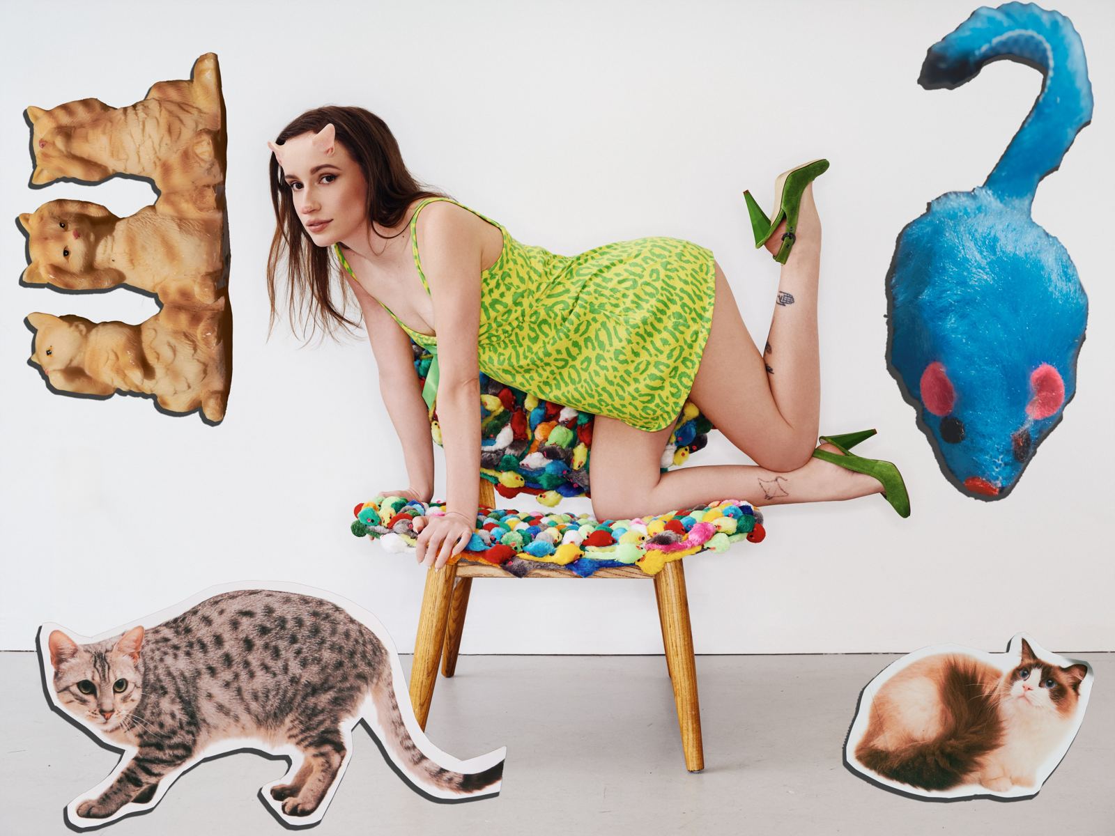 Gab Bois sur une chaise recouverte de souris en peluche, entourée de collages de chats